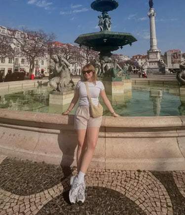 Customer Ann enjoying a sunny day near a fountain, wearing relaxed natural clothing, representing Kiseau’s sustainable lifestyle values.