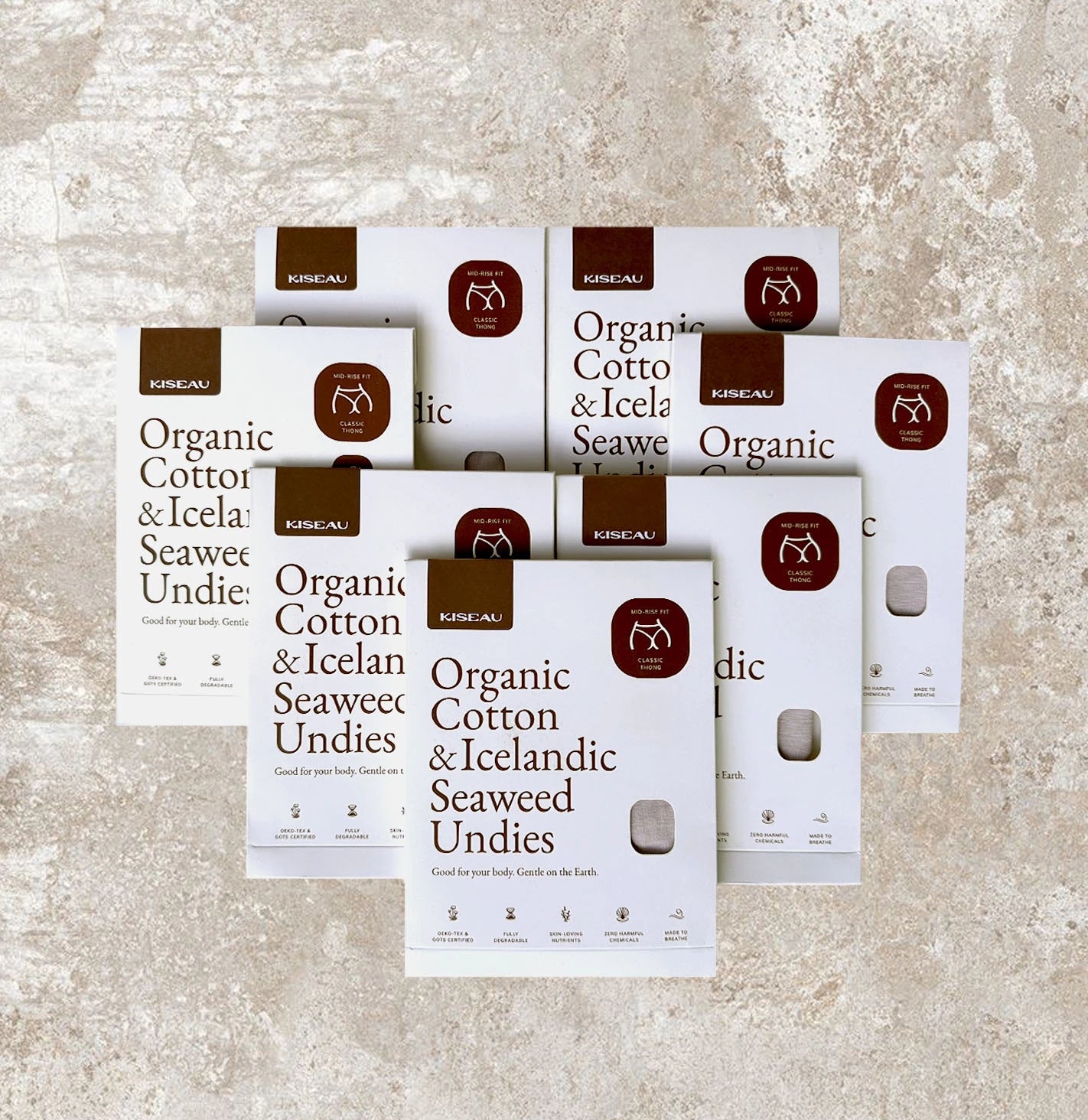 Seven Kiseau Organic Cotton & Icelandic Seaweed underwear boxes on textured stone surface, sustainable and plastic-free packaging.