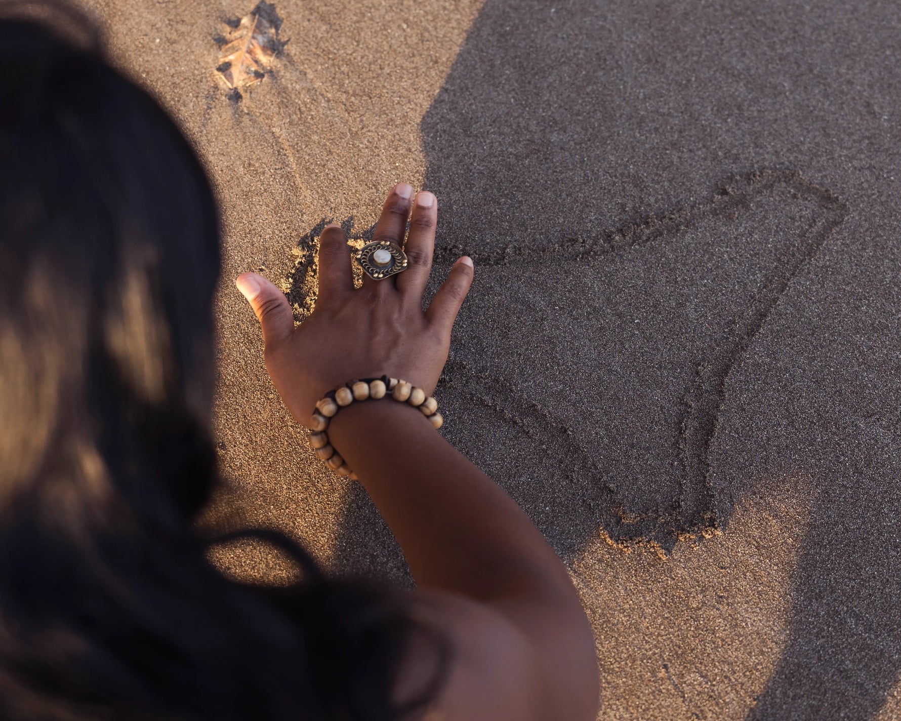 Hand drawing underwear outline in sand, symbolizing Kiseau organic cotton underwear and sustainable natural inspiration