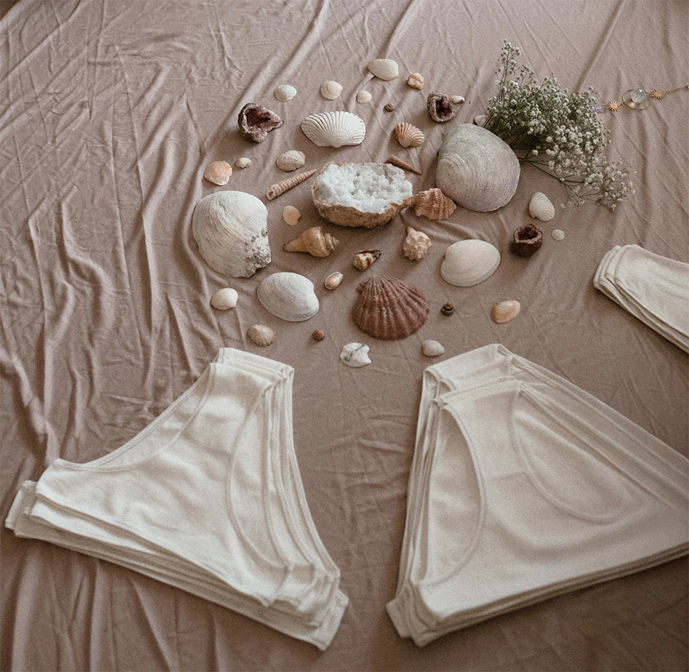 Flat lay of Kiseau organic cotton women’s underwear beside seashells and natural elements, highlighting sustainable eco-friendly design.