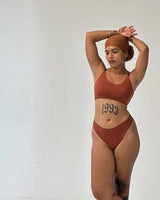 Model wearing Kiseau Terra Cotta Bralette and Cheeky Bikini in seaweed-infused organic cotton, arms raised, front view, studio