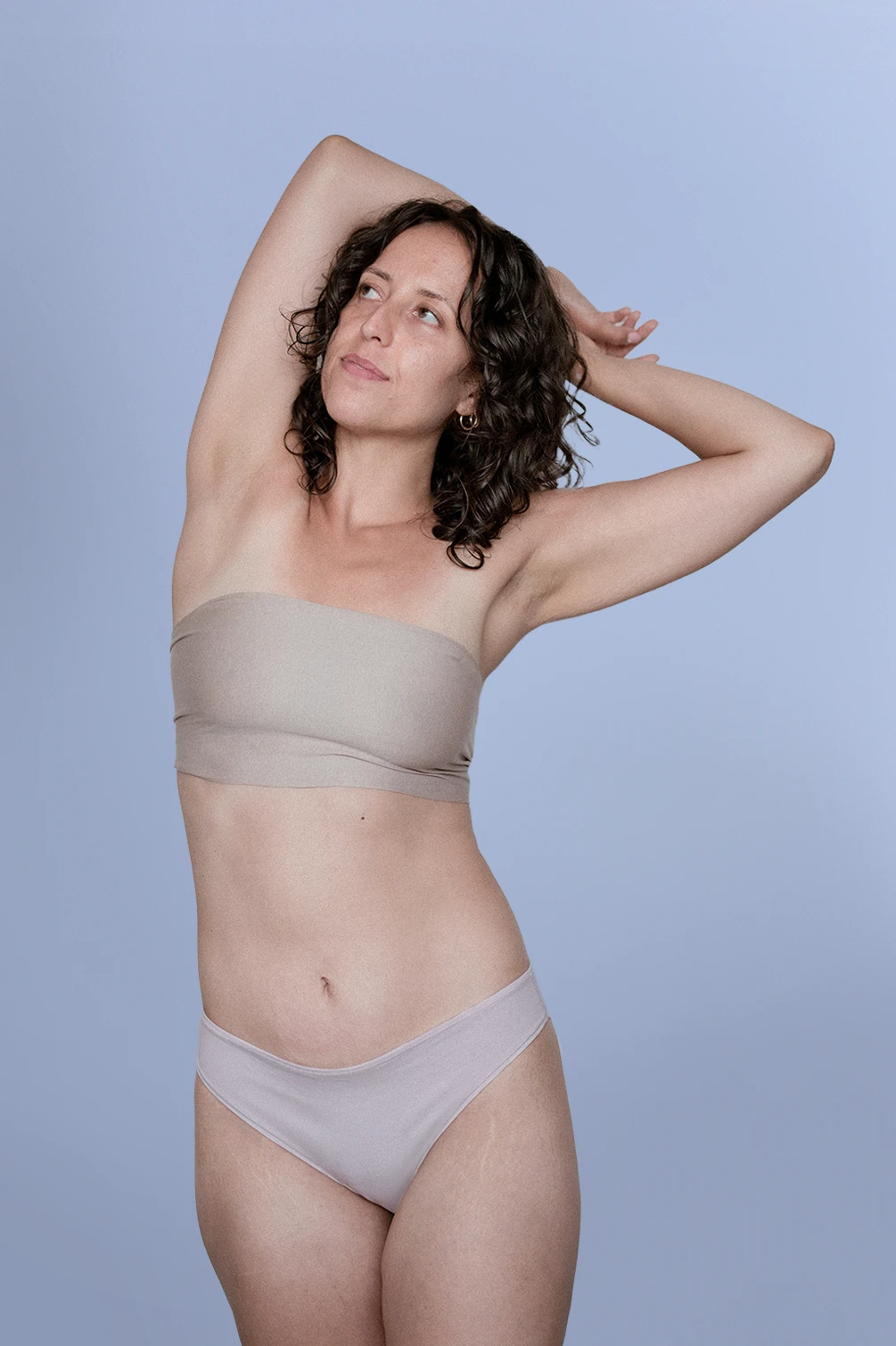 Kiseau women’s organic cotton bikini underwear, sustainable breathable design, model front view arms raised.