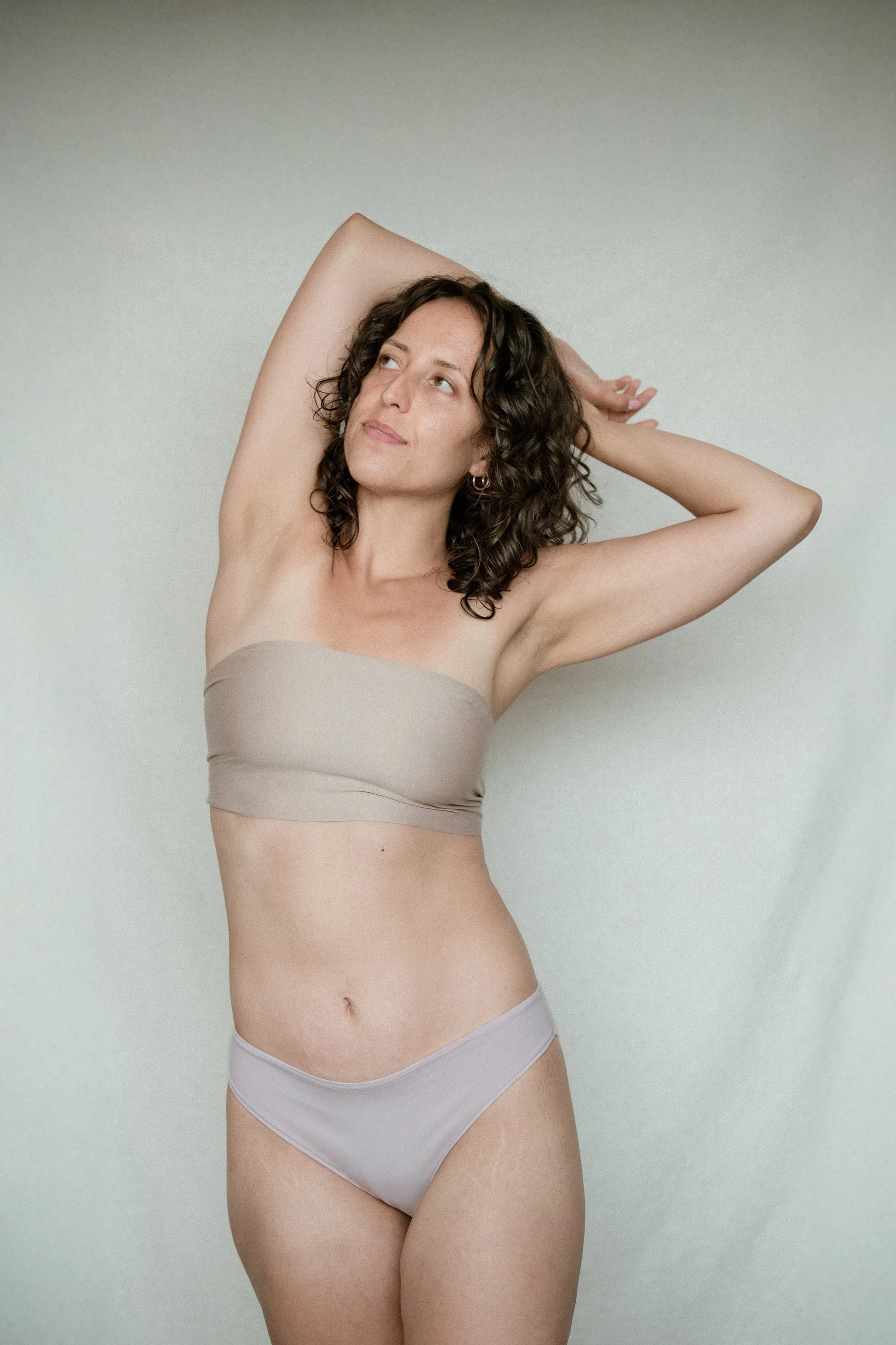 Kiseau women’s organic cotton bikini underwear, sustainable breathable design, model front view arms raised.