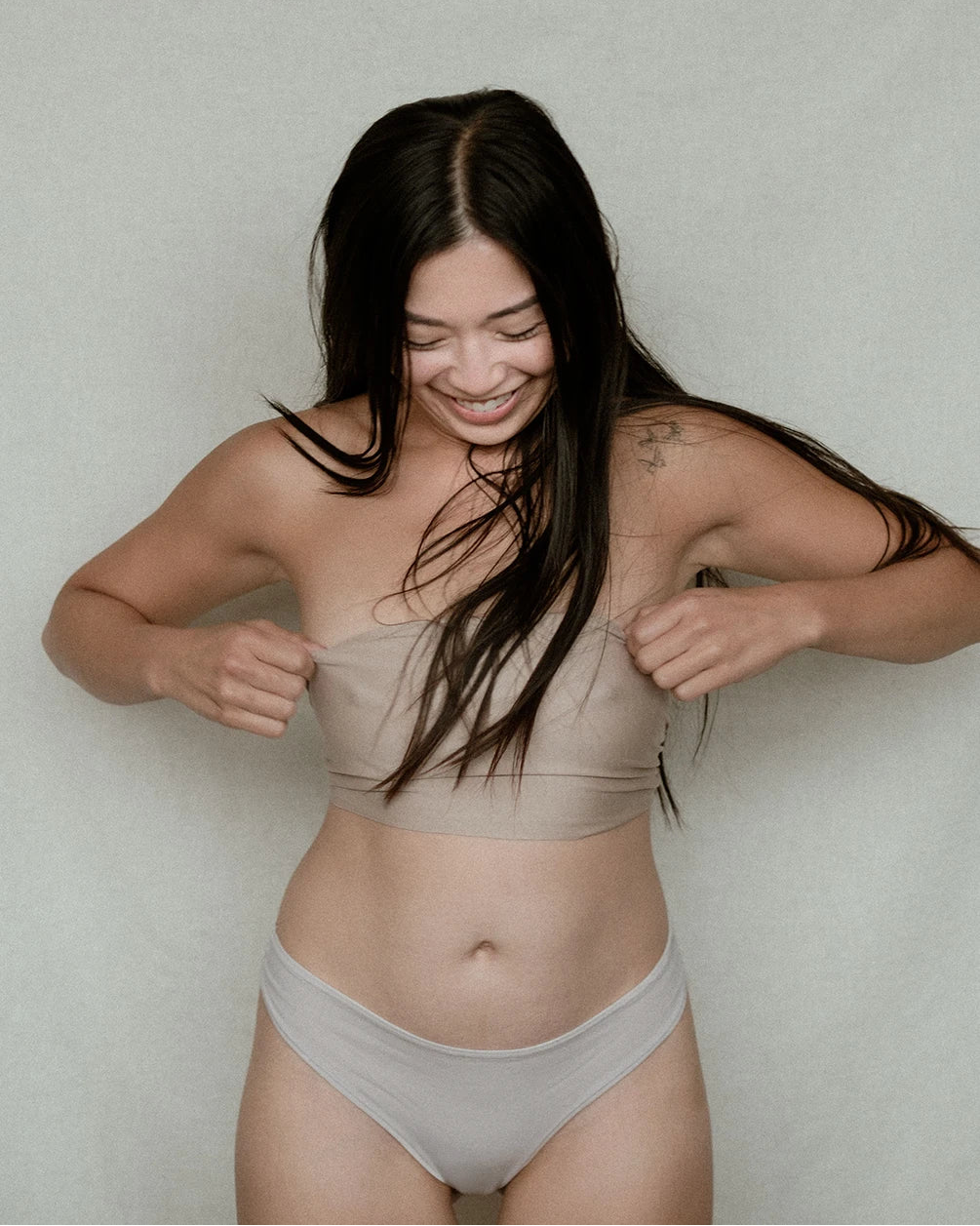 Woman modeling Kiseau organic cotton bikini underwear, breathable and eco-friendly, front view, looking down at undies with excitement