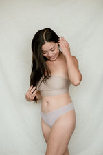 Woman modeling Kiseau organic cotton bikini underwear, breathable and eco-friendly, front view, looking at undies with excitement